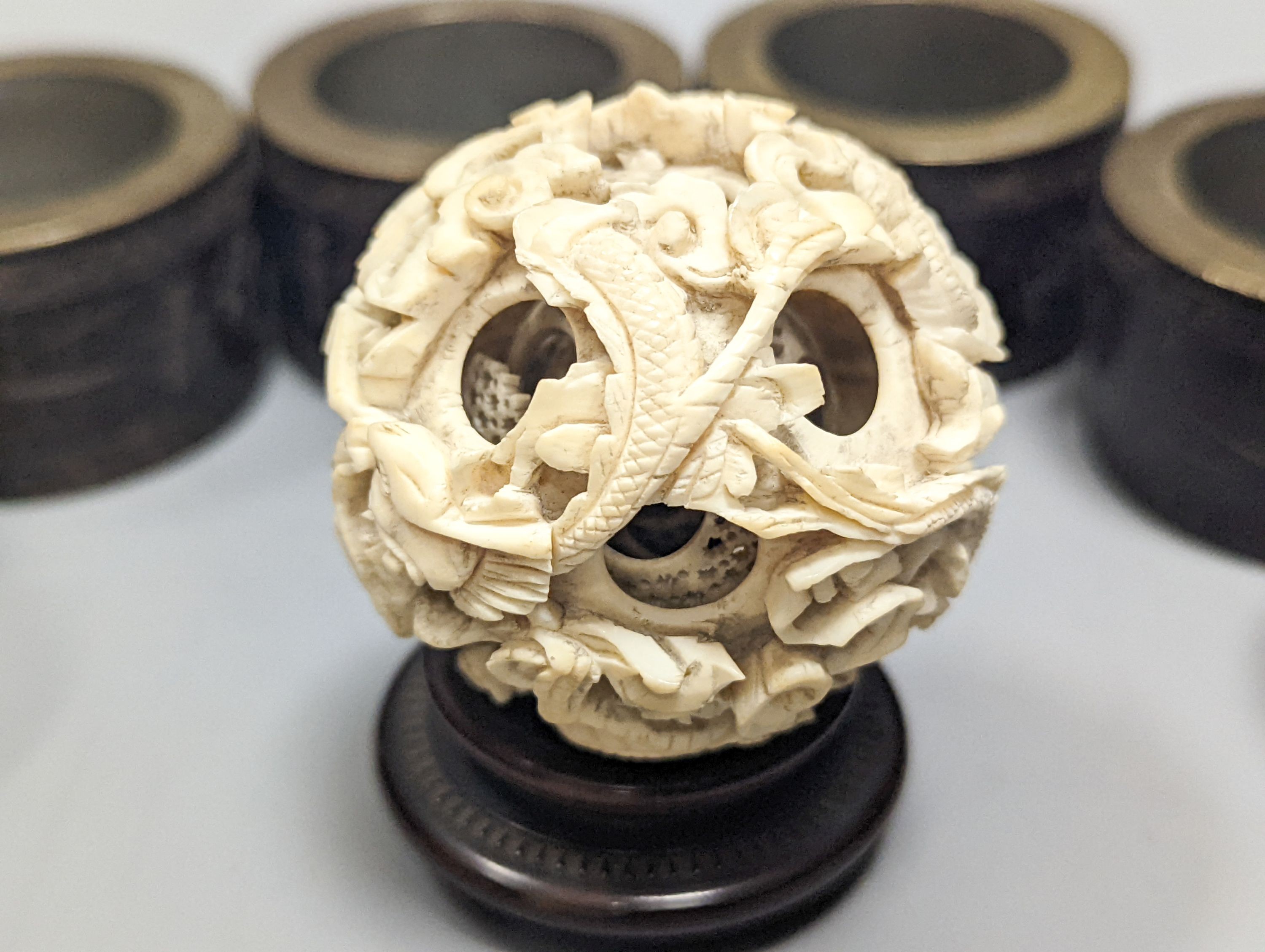 A Chinese ivory concentric puzzle ball, 6 Chinese coconut and brass mounted napkin rings.